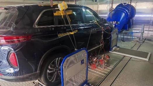 Photograph of an instrumented vehicle on a chassis dynamometer inside a climatic test cell.